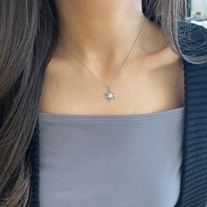 Female model wearing Diamond cluster star of david pendant - 14K gold weighing 2.58 grams
- 7 round diamonds weighing 0.09 carats