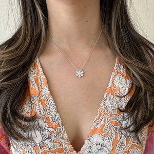 Female Model Wearing Round and Baguette Diamond Flower Pendant - 18K gold weighing 4.07 grams - 25 round diamonds weighing 0.13 carats - 12 slim baguettes weighing 0.64 carats